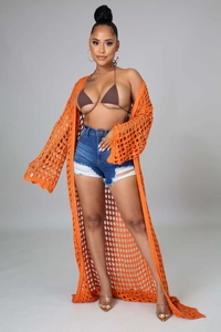 Detailed knit texture of a long orange crochet beach cover-up cardigan for summer