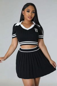 Detail of a two-piece black knitted sports set with pleated skirt and white stripes