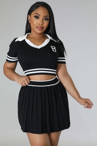 Detail of knitted crop top and pleated skirt with white stripe and letter B logo
