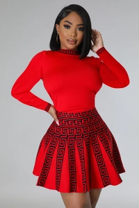 Detailed view of red knitted pleated skirt featuring black Greek key pattern border
