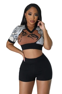 Detail of V-neck knit top showing the abstract face pattern and ribbed black trims