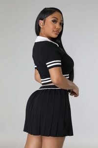 Detail of a two-piece knit sportswear set featuring a black polo top and pleated skirt