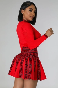 Detail of red knit dress showing Greek Key geometric pattern and pleated hem