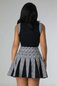 Back view of sleeveless knitted top and pleated skirt with Greek key pattern