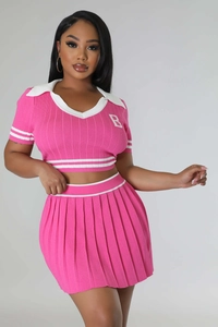 Detail of the pink knitted polo top featuring white stripe trim and a letter B patch