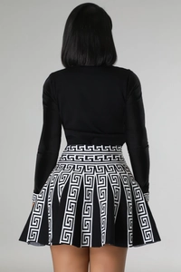 Back view of a long sleeve black top and knitted pleated skirt with Greek key pattern