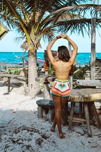 Detail of bohemian crochet bikini set with colorful geometric pattern shorts on a beach