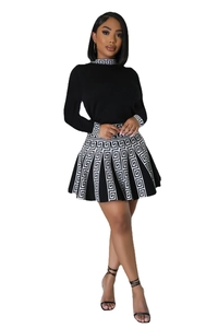Detail of knit long-sleeve top and pleated skirt with Greek key pattern trimming
