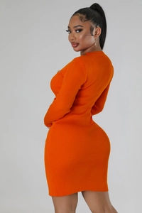 Detailed close-up of bright orange ribbed knit dress featuring small gold metal ornaments