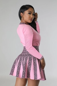 Detail of pink knitted long-sleeve dress with black Greek key pattern on cuffs and hem
