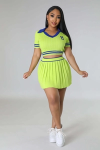 Detail of neon green polo top with blue stripes, pleated skirt, and letter B embroidery
