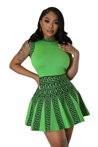 Detailed view of green sleeveless knit top and pleated skirt with Greek meander patterns