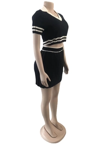 Detail view of black knitted two-piece set with white stripes on short polo top and pleated skirt