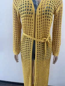 Detail of long bright yellow crochet knit beach cover-up with openwork pattern and belt