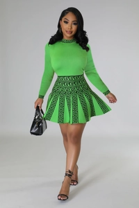 Detailed view of the green knit dress featuring black Greek Key patterns on cuffs and waist