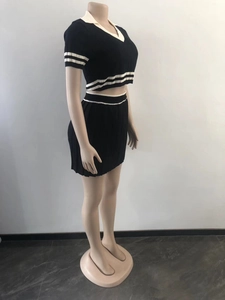 Detail view of black knit crop top and pleated skirt set with white stripe accents