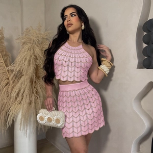 Detalle del conjunto de punto rosa con patrones ondulados dorados y bordes festoneados