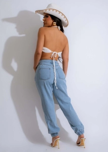 Dettaglio del top all'americana all'uncinetto bianco con lacci e pantaloni jogger in denim