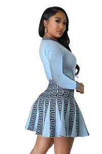 Detail of light blue knit top and pleated skirt featuring black Greek key pattern trim