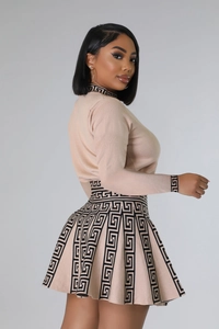 Detail view of knit two-piece set featuring black meander greek key patterns on beige fabric