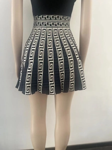 Close-up of sleeveless pleated dress with geometric Greca pattern and slim high waist fit