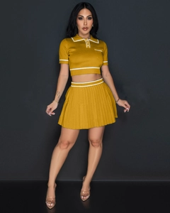 Detail of mustard yellow knit two-piece set with pleated skirt and striped polo collar