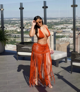 Detail of bright orange two-piece crochet bikini set with long tassel mesh skirt