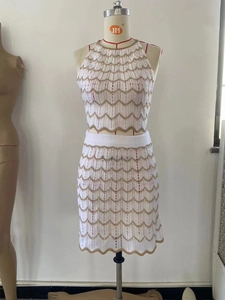 Detalle de conjunto de ganchillo blanco con rayas doradas onduladas y tejido calado