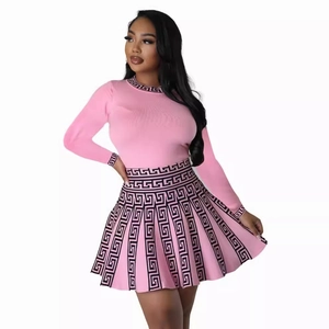 Pink knit two-piece set with long sleeves and pleated skirt featuring Greek key patterns