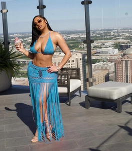 Detail of turquoise crochet knit long beach skirt with fringe on a rooftop setting