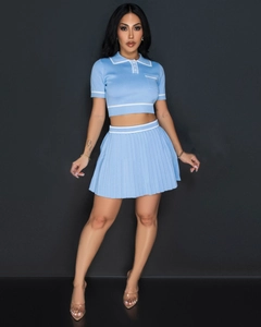 Detail of light blue pleated knit set featuring white polo collar and stripe accents