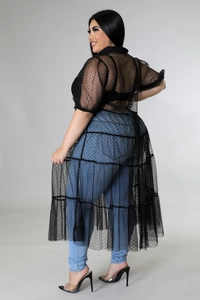 Detail der Plus-Size-Tunika aus schwarzem Polka-Dot-Mesh mit Jeans an einem Model