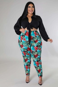 Close-up of tropical floral print leggings and black tie-front shirt on a plus size model