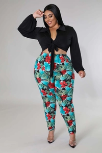 Detail of plus size two-piece set featuring tropical print pants and lace-up black shirt