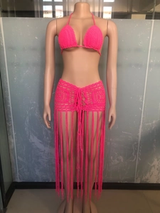 Detailed close-up of pink crochet knit texture and long fringe on the beach skirt