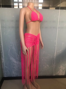Detail of hot pink crochet knit fabric with long fringe tassels on beach skirt