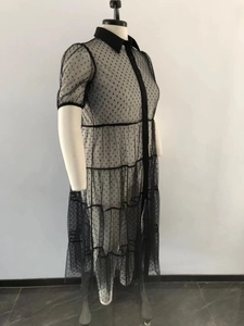 Detail eines schwarzen gepunkteten Mesh-Kleides in Übergröße mit Rüschen und Knöpfen