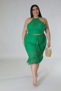 Detail of green knit two-piece set featuring crochet textures and fringe tassels on the skirt