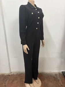 Detail of long sleeve jumpsuit featuring contrast white buttons and polo collar design
