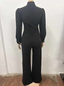 Detail view of black long sleeve jumpsuit featuring back cut and silver button cuffs