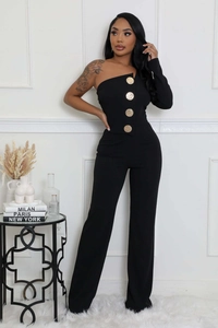 Détail d'une combinaison noire à une épaule avec coupe asymétrique et grands boutons dorés