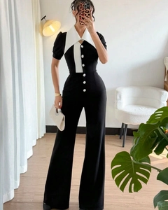 Detail shot of contrasting white peak lapels and decorative buttons on a black jumpsuit
