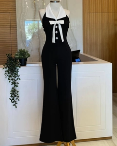 Detail eines schwarzen Neckholder-Jumpsuits mit weißem Revers und Kristallknöpfen
