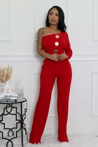 Détail d'une combinaison rouge asymétrique avec de gros boutons dorés et jambes larges