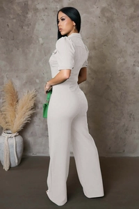 Detail of light grey short sleeve jumpsuit featuring a classic collar and button accents