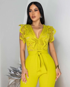 Detail of lime green lace jumpsuit showing intricate floral cutouts and tie-up belt waist