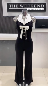 Detailansicht des schwarzen Neckholder-Jumpsuits mit weißem Revers und dekorativer Schleife