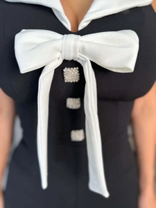 Detailansicht des Overalls mit großer weißer Schleife und eleganten Perlenknöpfen