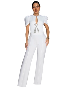 Detail of white jumpsuit with puff sleeves and a silver rhinestone bow on the neckline