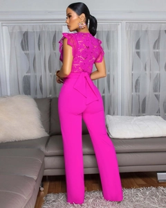Close-up detail of hot pink jumpsuit featuring lace floral patterns and a large back waist bow